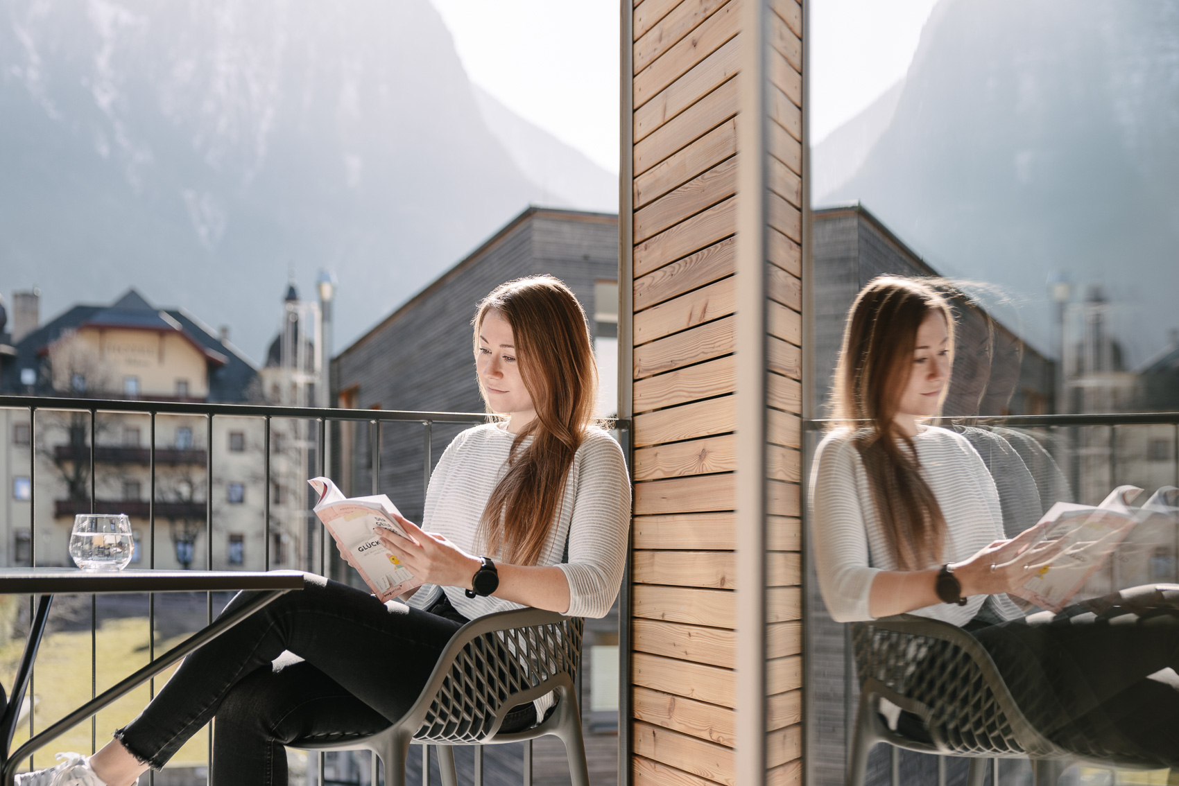 Eine Frau liest entspannt auf einem Balkon von MyAlps Tirol in Oetz, mit Blick auf die Alpen. Die Hotelfotografie fängt einen Moment der Ruhe und Geborgenheit ein.