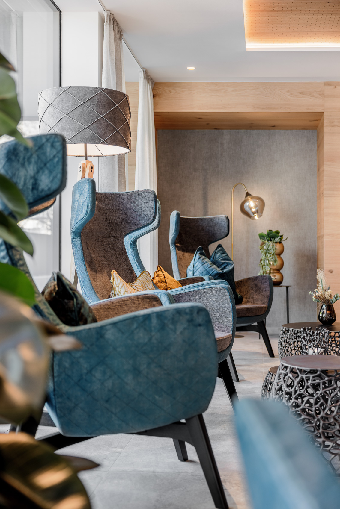 Moderne, bequeme Sessel laden im Loungebereich des MyAlps Tirol in Oetz zum Entspannen ein. Das Design kombiniert Holzelemente und stilvolle Lampen für eine gemütliche Atmosphäre.